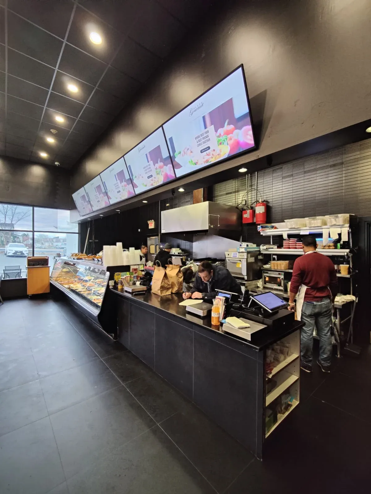 Row of landscape menu board kit screens hung over a deli counter